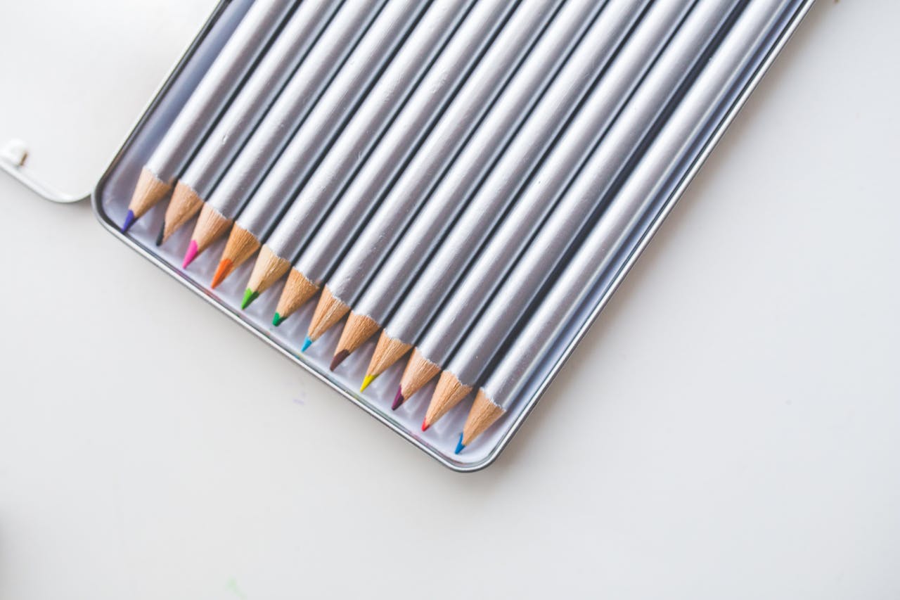 Close-up of a set of colorful pencils neatly arranged in a metal case, ideal for drawing and design.